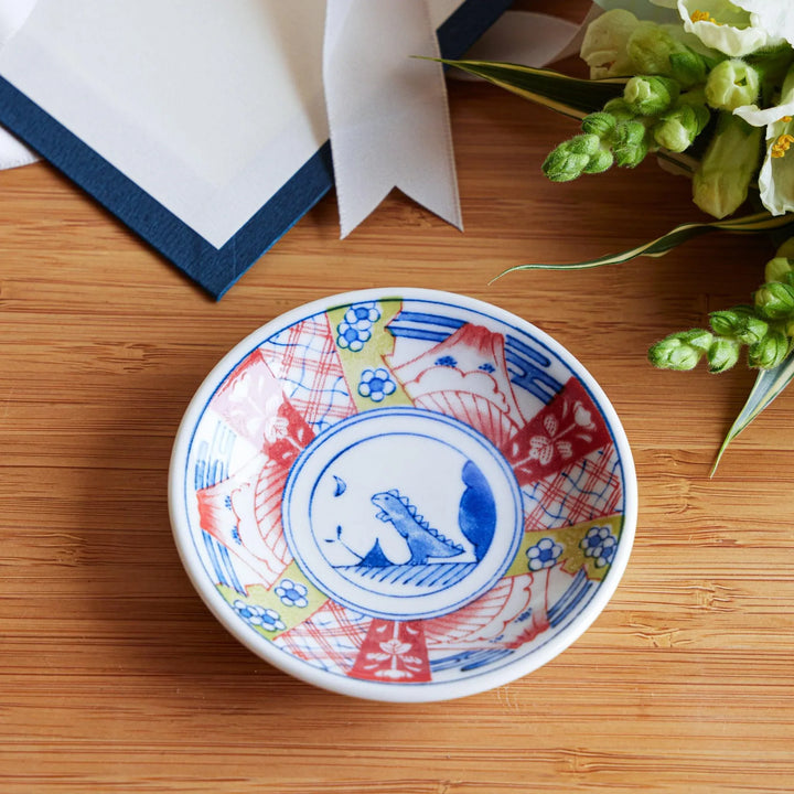 Set of four Japanese porcelain plates in gift box each with blue and red dinosaur design decoration.