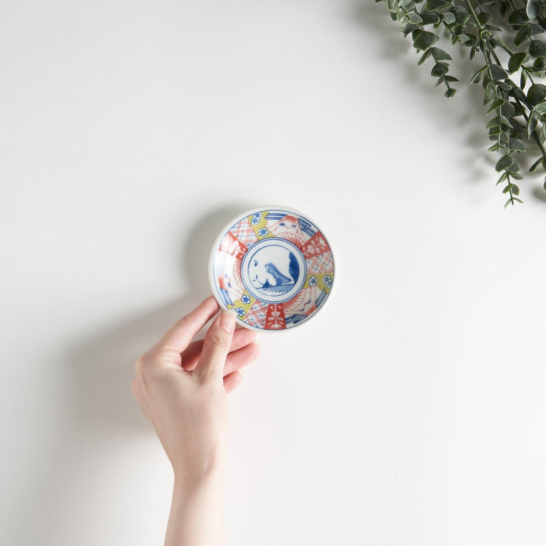 Set of four Japanese porcelain plates in gift box each with blue and red dinosaur design decoration.
