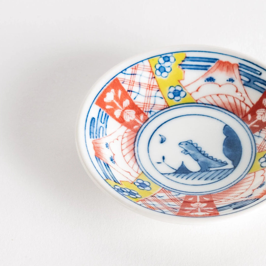 Set of four Japanese porcelain plates in gift box each with blue and red dinosaur design decoration.