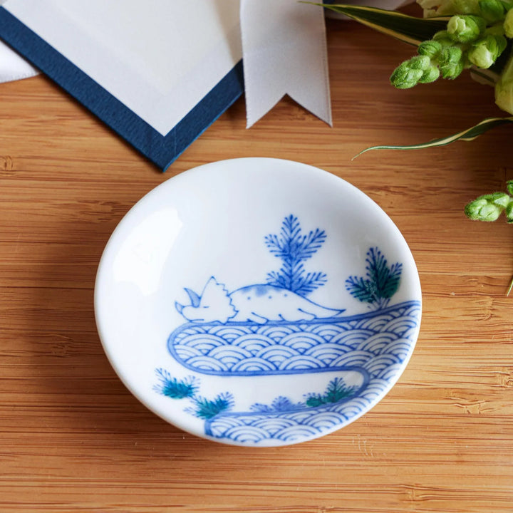 Set of four Japanese porcelain plates in gift box each with blue and red dinosaur design decoration.