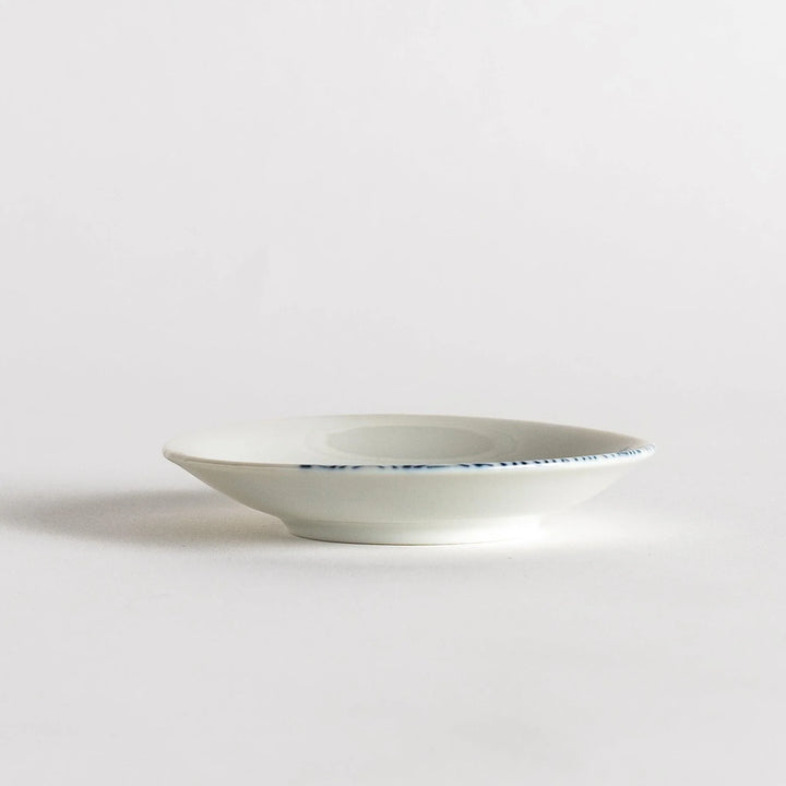 Set of four Japanese porcelain plates in gift box each with blue and red dinosaur design decoration.