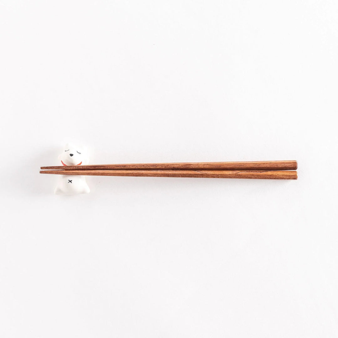 A wide view of the dog-shaped chopstick rest with chopsticks placed across its back, showcasing the playful design.