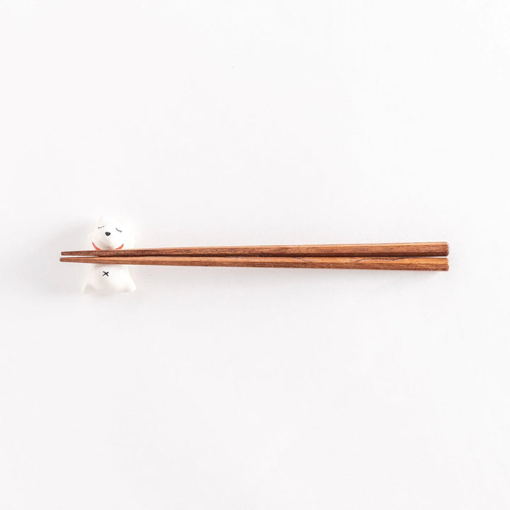A wide view of the dog-shaped chopstick rest with chopsticks placed across its back, showcasing the playful design.