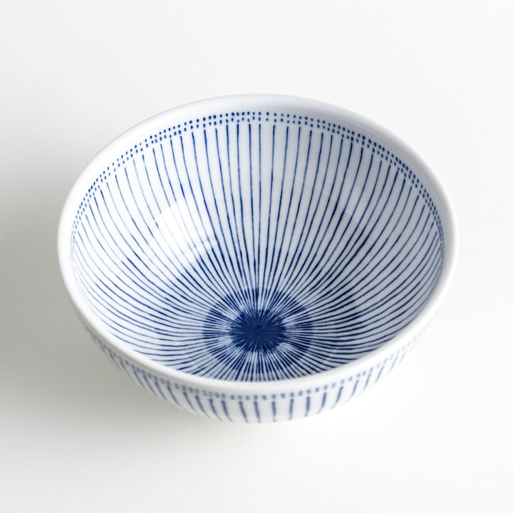 A white porcelain bowl with thin blue vertical stripes and dotted patterns around the rim.