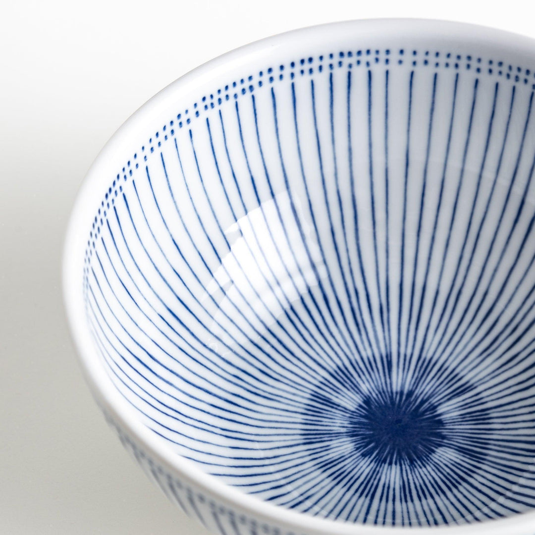 A white porcelain bowl with thin blue vertical stripes and dotted patterns around the rim.