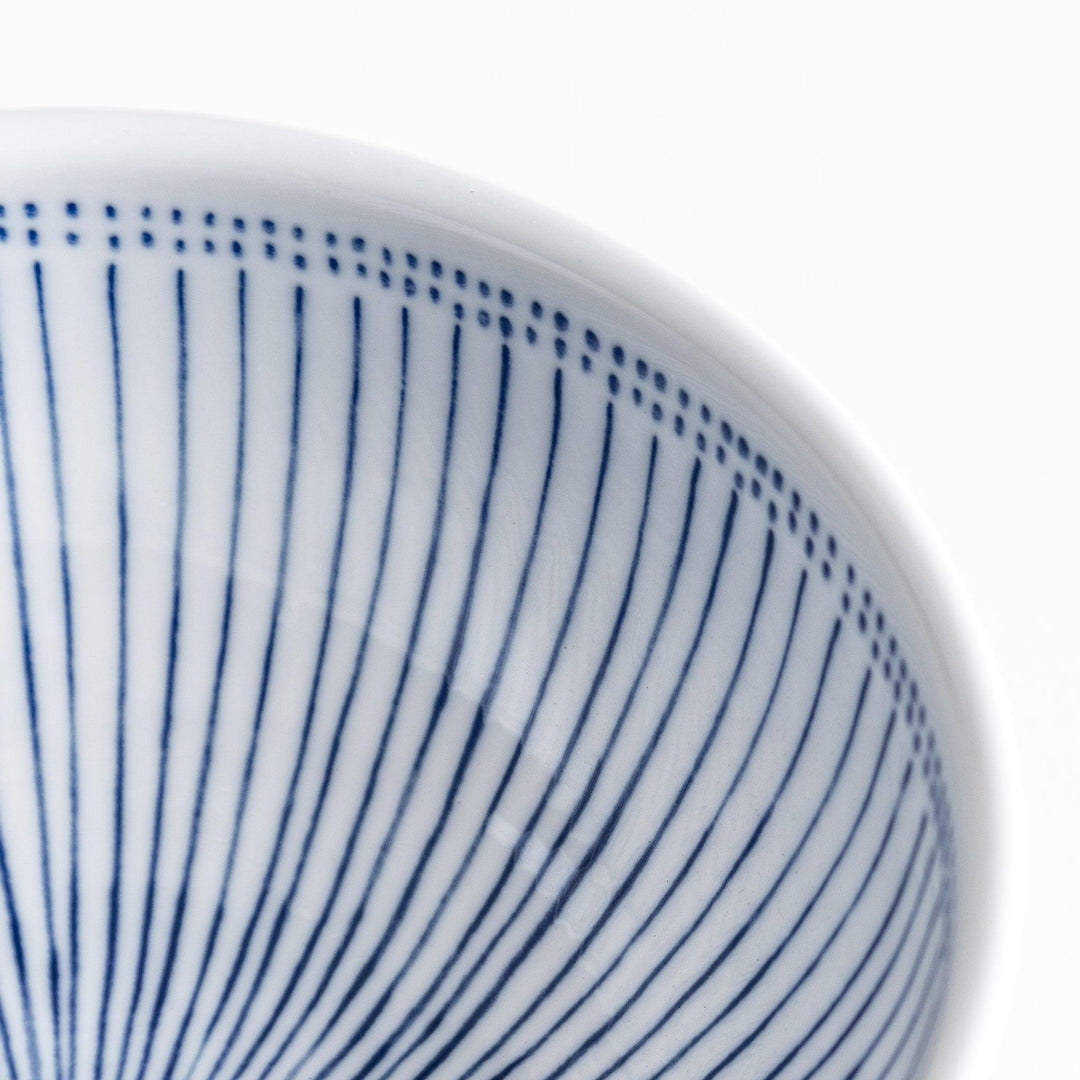 A white porcelain bowl with thin blue vertical stripes and dotted patterns around the rim.