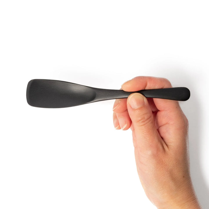 Matte black aluminum ice cream spoon with flat edge designed for easy scooping of firm frozen desserts.