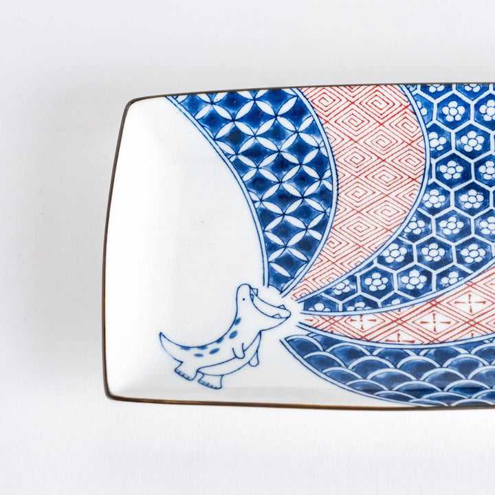 Rectangular plate with Edo patterns and blue dinosaur illustration served with golden pan fried gyoza.