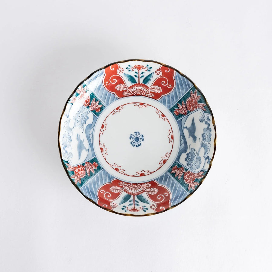 Top view of a decorative plate featuring intricate designs in red, blue, and green colors with floral and dinosaur motifs.