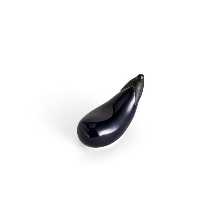 Glossy purple ceramic eggplant chopstick rest with black stem adding unique charm to Japanese table setting.
