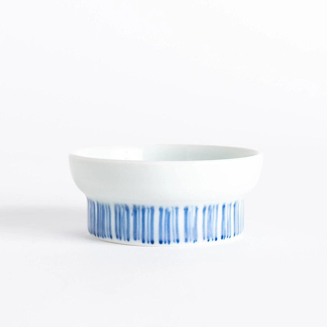 Small raised Japanese sauce dish with blue eggplant design inside and vertical blue lines along the edge.