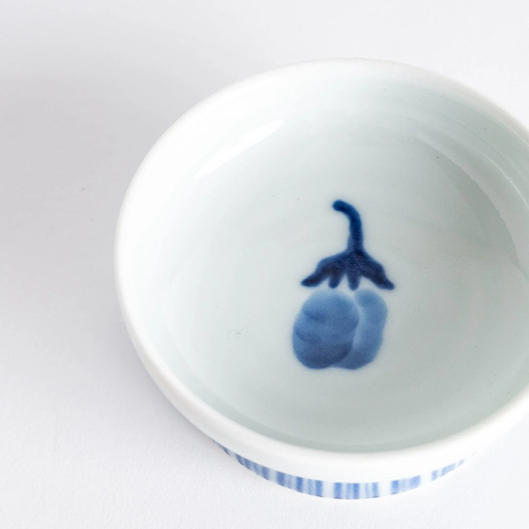 Small raised Japanese sauce dish with blue eggplant design inside and vertical blue lines along the edge.