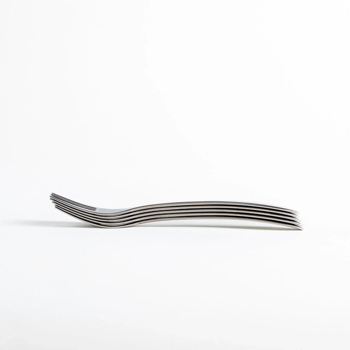 Side view of a stack of stainless steel forks, highlighting their thin profile.