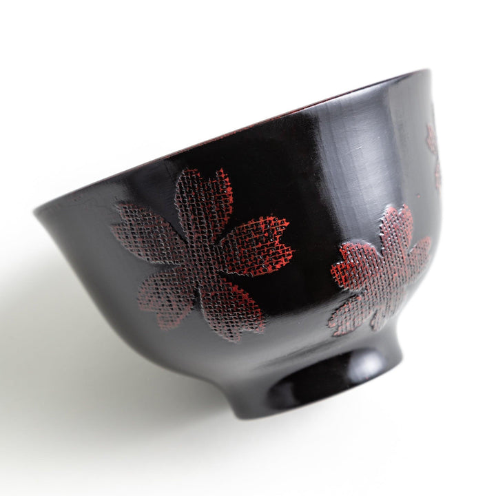 A lacquered bowl featuring a textured black floral design and a smooth, polished finish. Available in black or red.