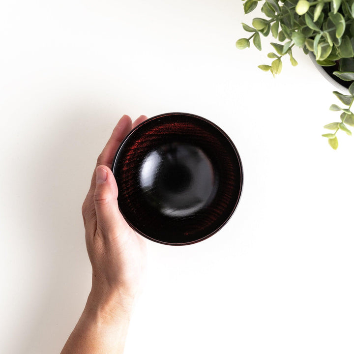 A lacquered bowl featuring a textured black floral design and a smooth, polished finish. Available in black or red.
