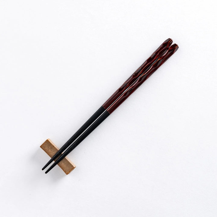 Ember color chopstick resting on a chopstick rest, highlighting its warm, rich hue and intricate design.