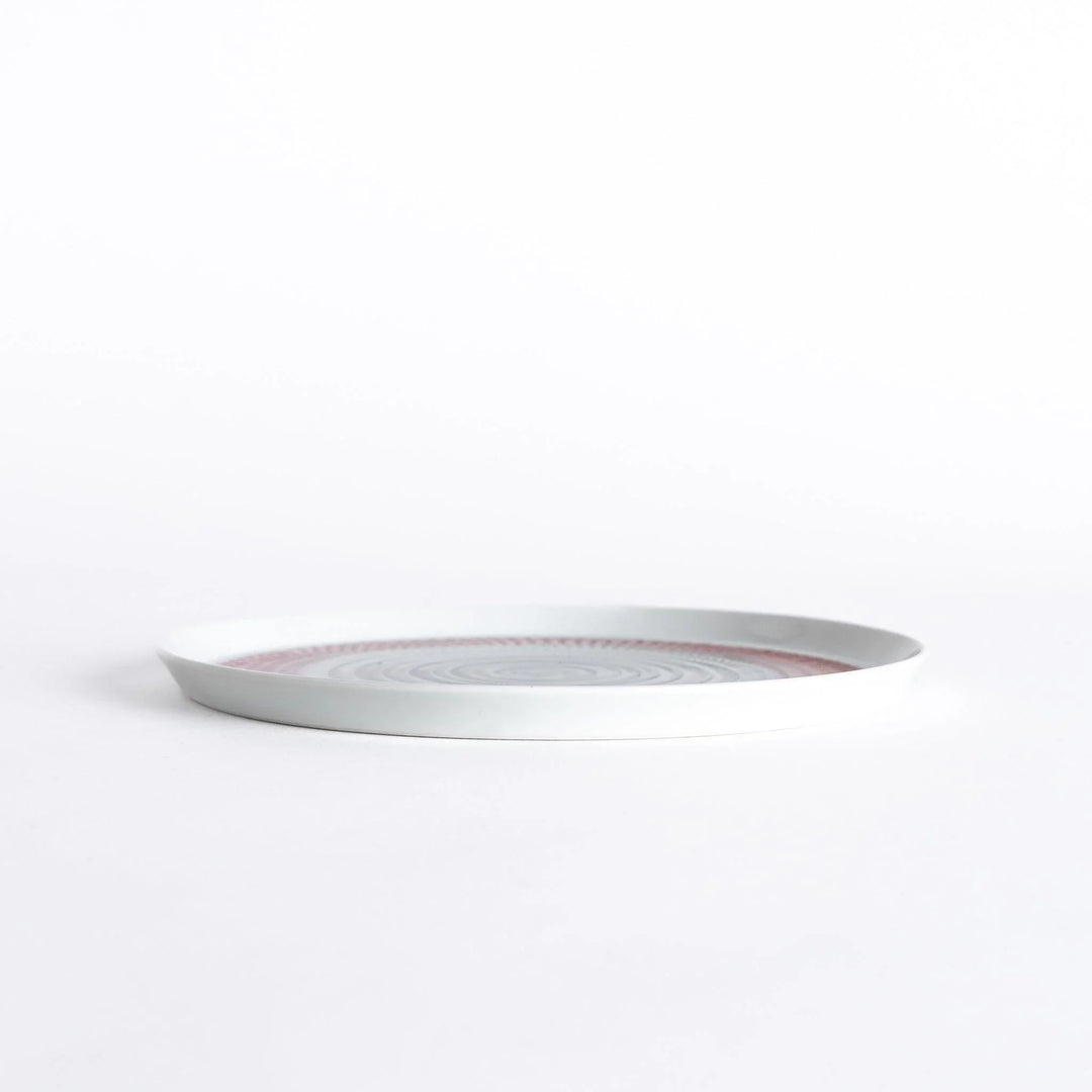 Side view of the plate, showcasing its sleek profile and the vibrant red spiral design.