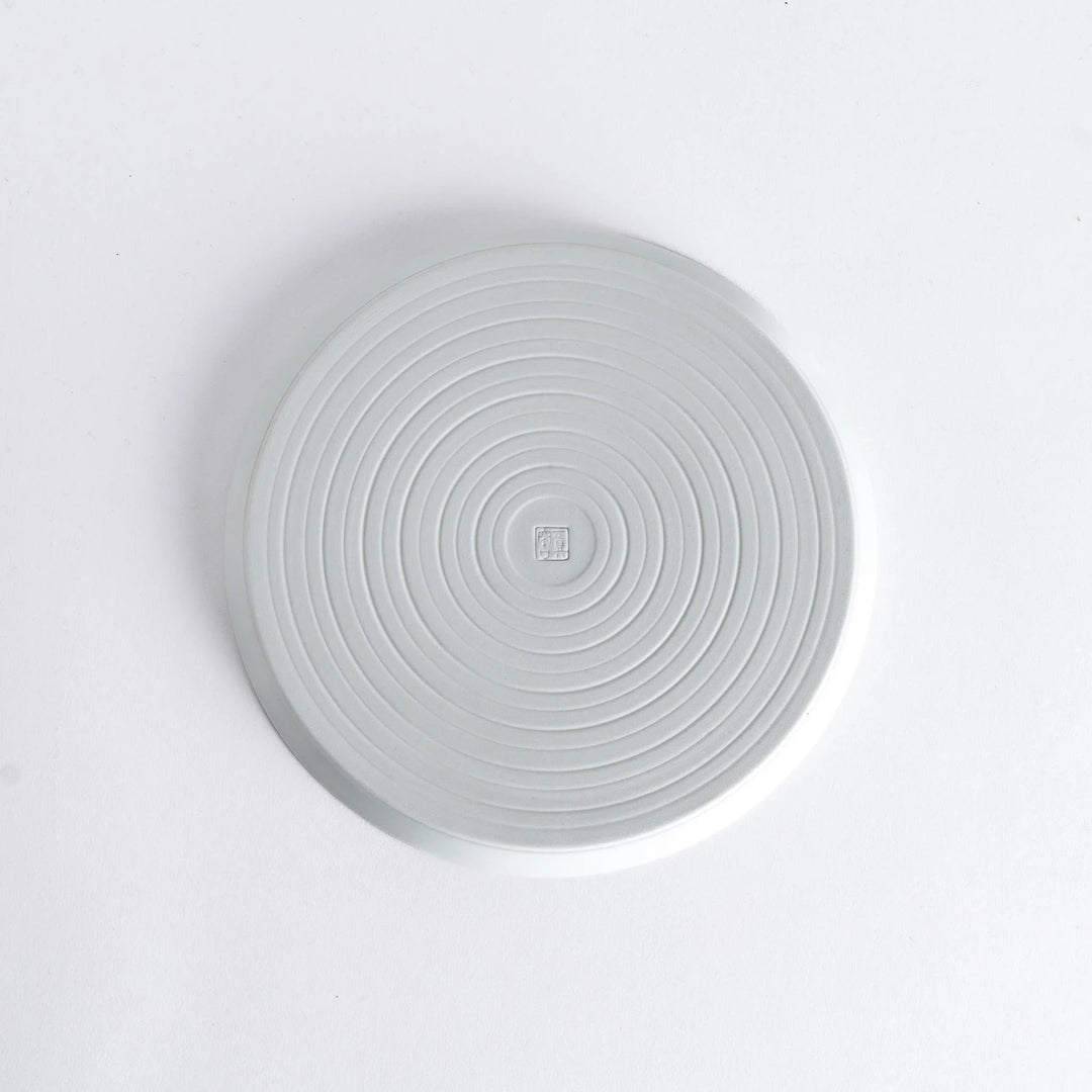 Bottom view of the plate, revealing a clean white surface with a small maker’s mark at the center.