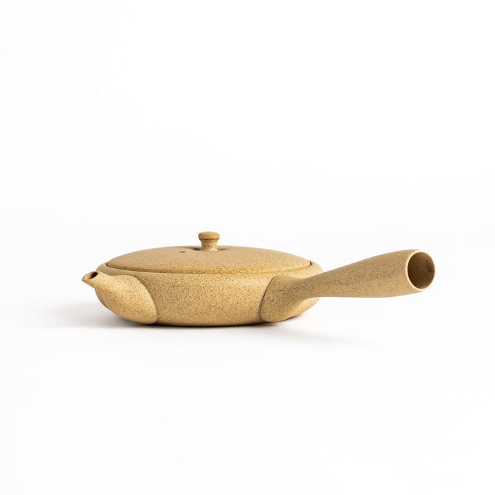 Sleek beige teapot with flat body and side handle offering minimalist design for refined tea serving.