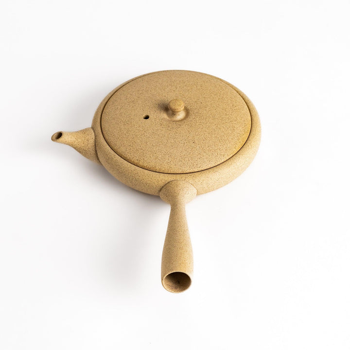 Sleek beige teapot with flat body and side handle offering minimalist design for refined tea serving.