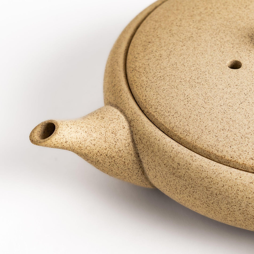 Sleek beige teapot with flat body and side handle offering minimalist design for refined tea serving.