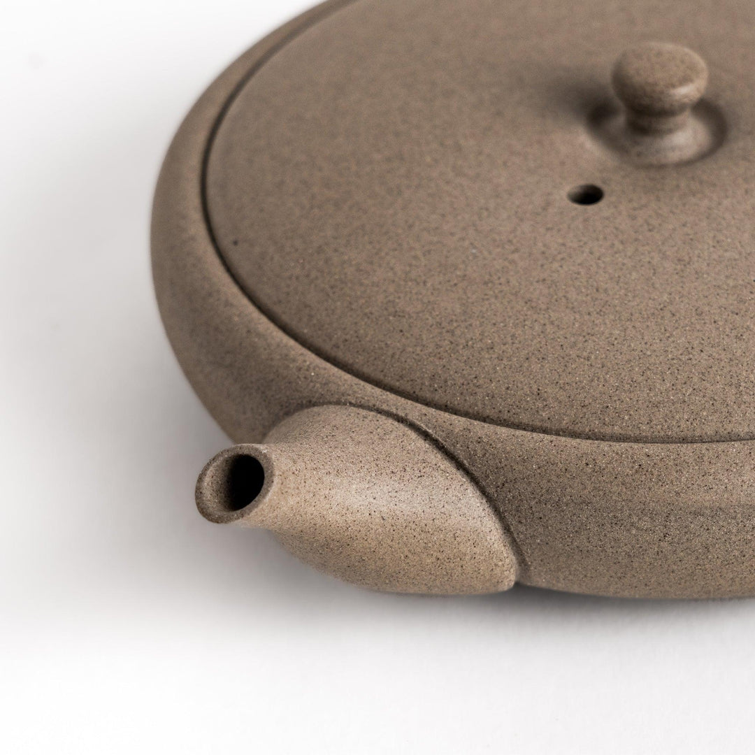 Sleek gray teapot with flat body and side handle offering minimalist aesthetic for modern tea setting.