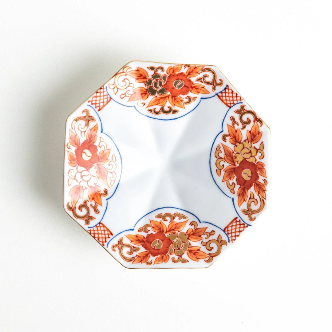 Octagonal plate with ornate orange floral patterns on a white background.
