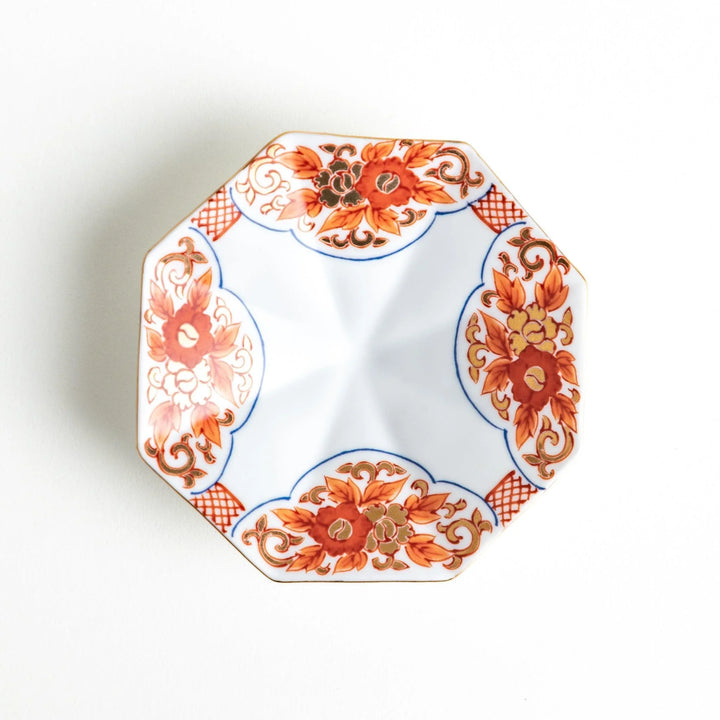 Octagonal plate with ornate orange floral patterns on a white background.
