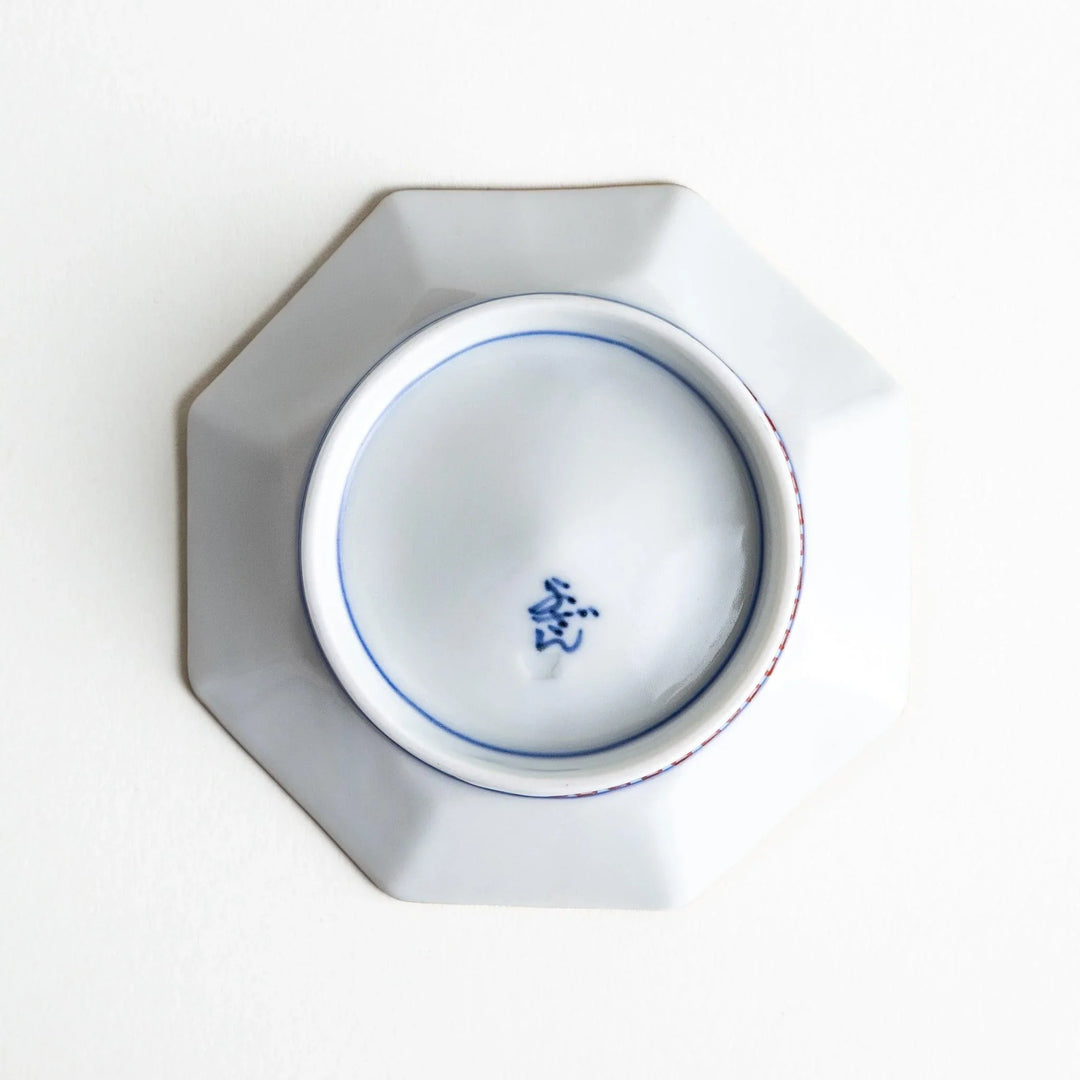 Octagonal plate with ornate orange floral patterns on a white background.
