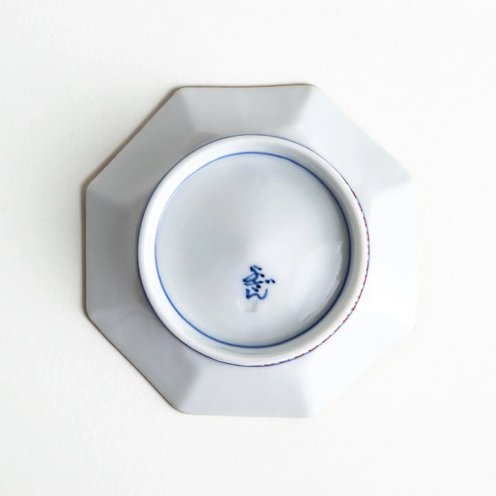 Octagonal plate with ornate orange floral patterns on a white background.
