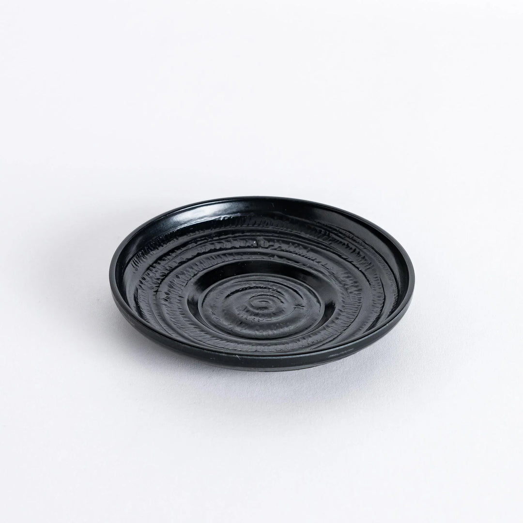 Angled view of the black saucer, highlighting its sleek design and gentle curve.