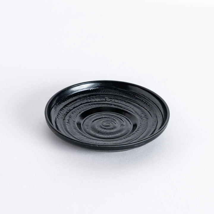 Angled view of the black saucer, highlighting its sleek design and gentle curve.