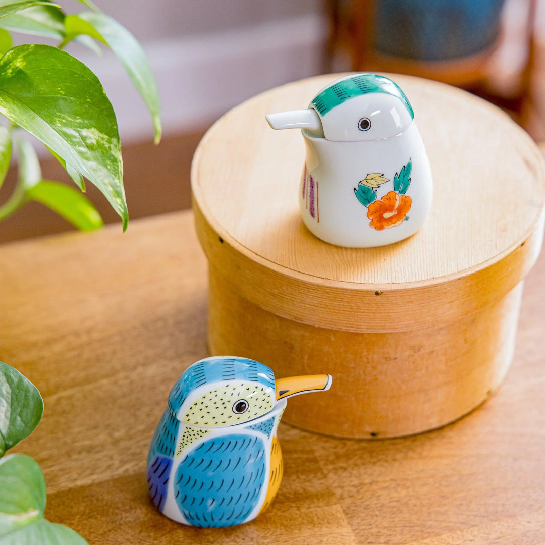 Japanese porcelain soy sauce dispensers shaped like birds with floral and kingfisher designs, displayed on a wooden table