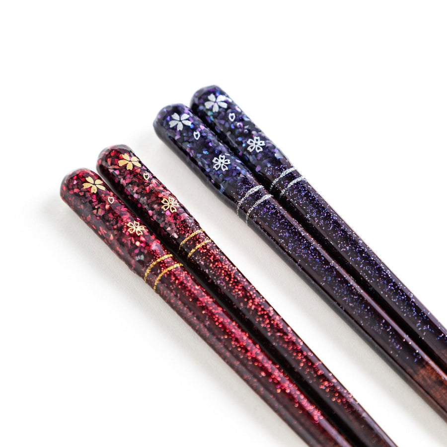 A pair of chopsticks with a sleek design featuring glitter accents and small floral patterns in deep red and navy blue, adding a touch of sparkle to your dining experience.