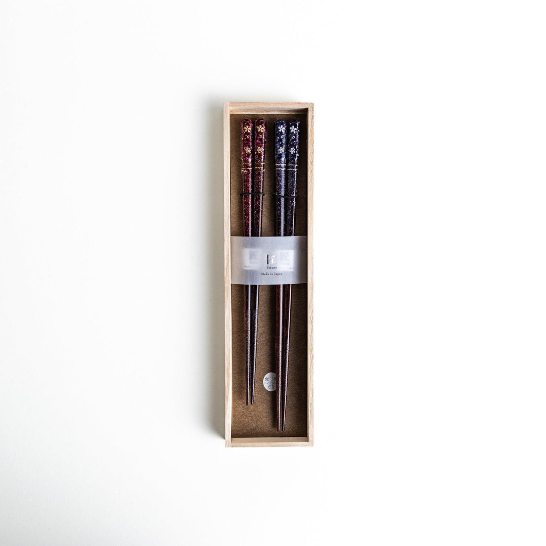 A pair of chopsticks with a sleek design featuring glitter accents and small floral patterns in deep red and navy blue, adding a touch of sparkle to your dining experience.