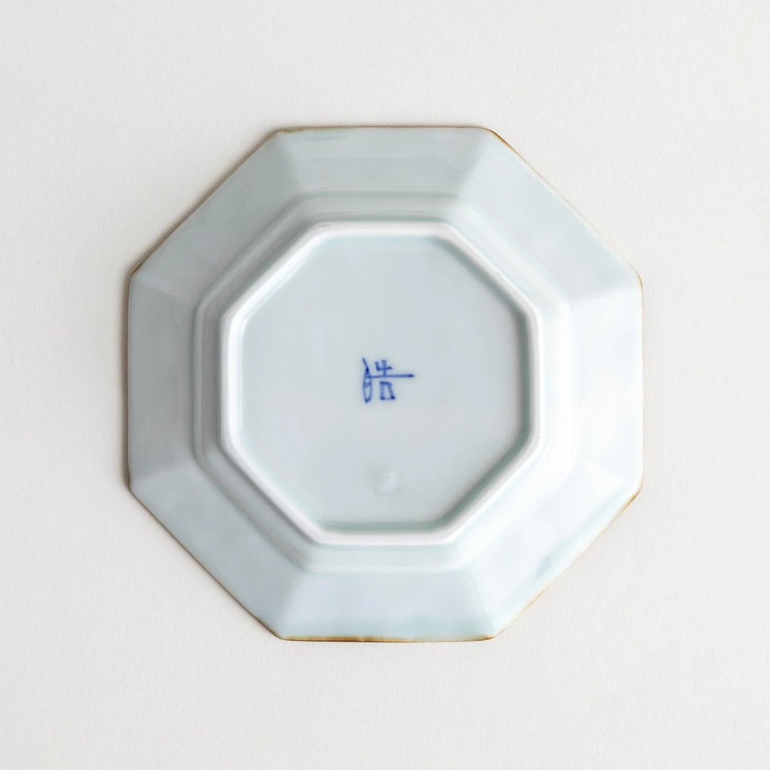 Octagonal white porcelain dessert plate with a blue floral motif and brown accent trim.