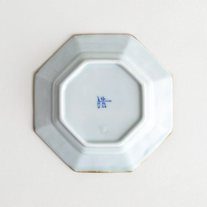 Octagonal white porcelain dessert plate with a blue floral motif and brown accent trim.
