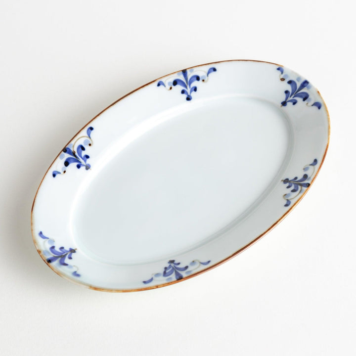 A porcelain oval salad plate, decorated with blue and white floral motifs and brown accent trim.