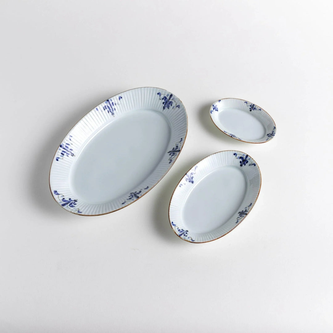 Three piece oval plate set with ridged design and blue floral motifs including large medium and small plates.