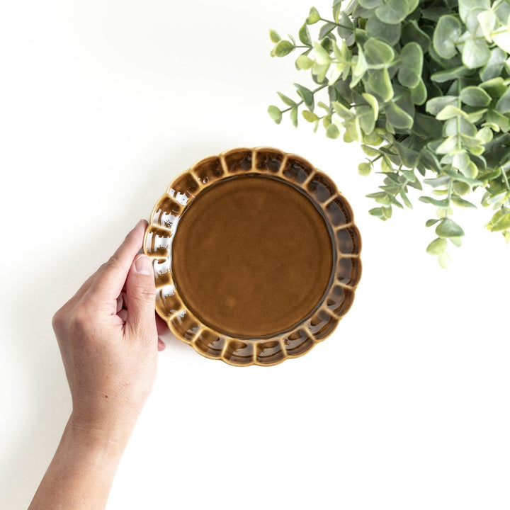 Round, dark brown or olive colored dessert plate with a scalloped edge, featuring a glossy finish.