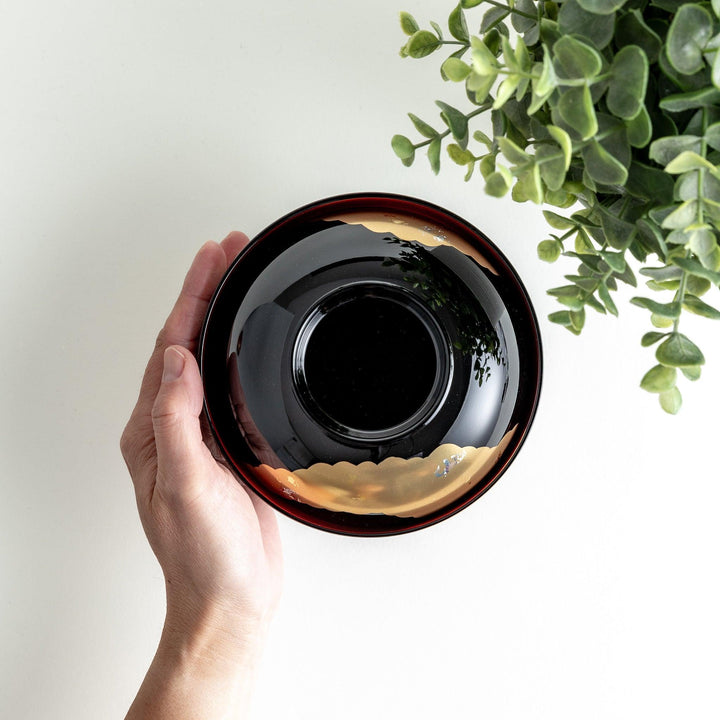 A lacquered soup bowl with a gold-painted cloud and crane motif. Available in red or black.