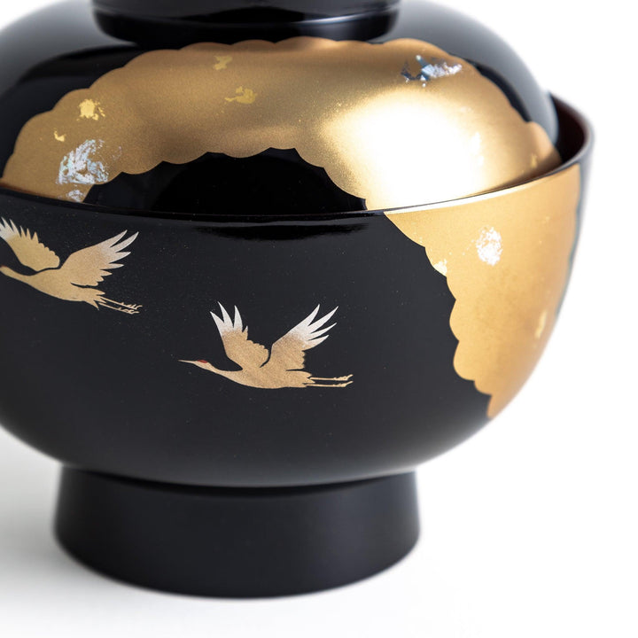 A lacquered soup bowl with a gold-painted cloud and crane motif. Available in red or black.