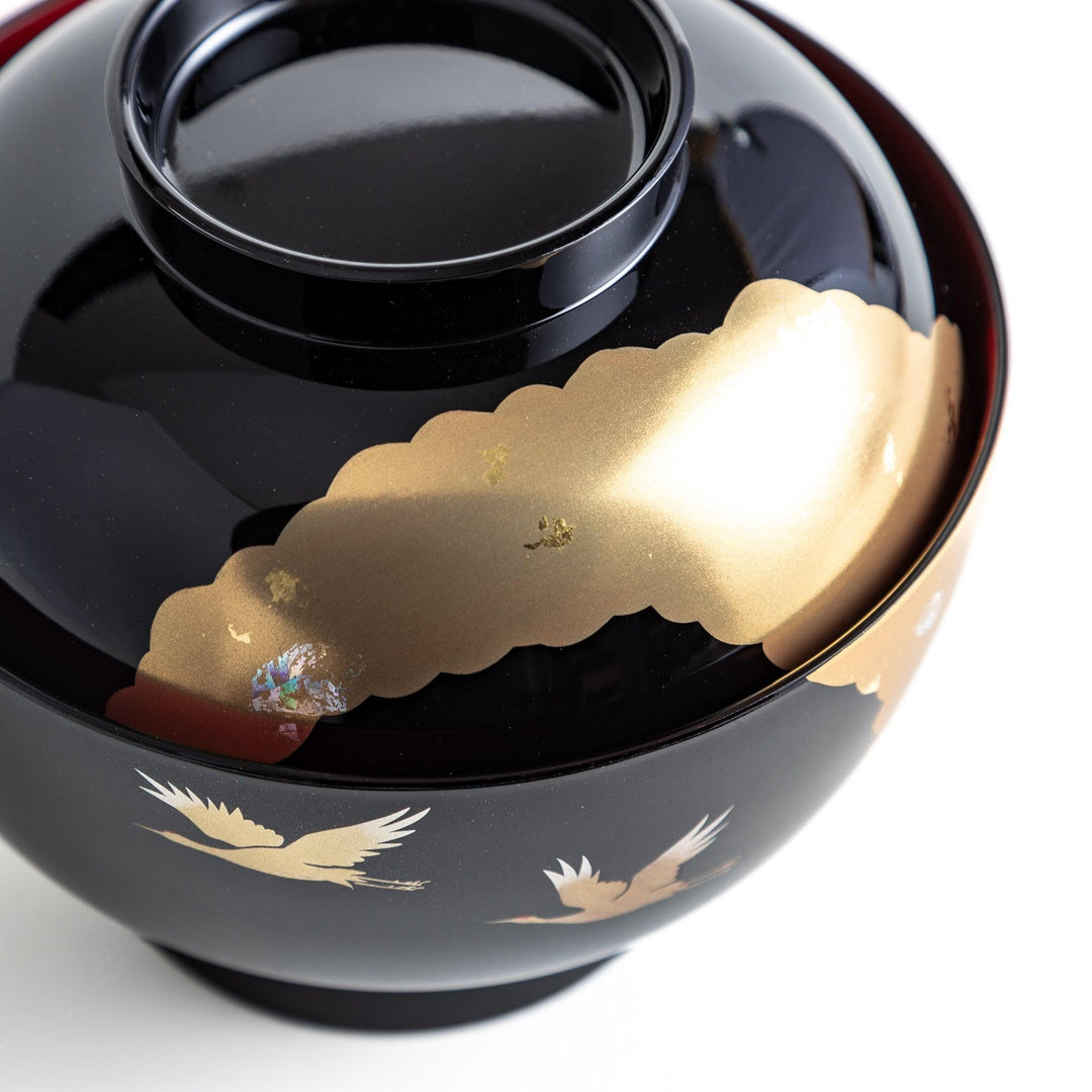 A lacquered soup bowl with a gold-painted cloud and crane motif. Available in red or black.