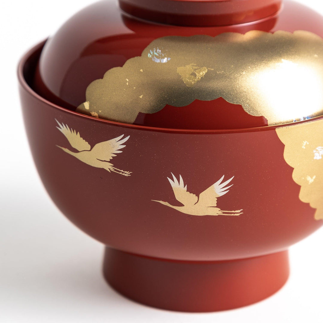 A lacquered soup bowl with a gold-painted cloud and crane motif. Available in red or black.