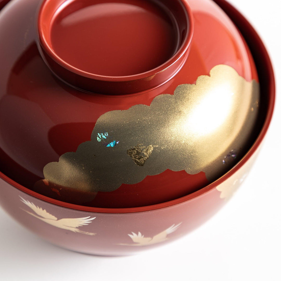 A lacquered soup bowl with a gold-painted cloud and crane motif. Available in red or black.