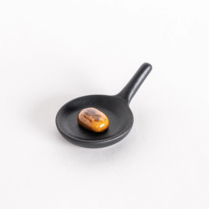 Frying pan hamburger chopstick rest featuring detailed design adding fun and playful touch to dining.