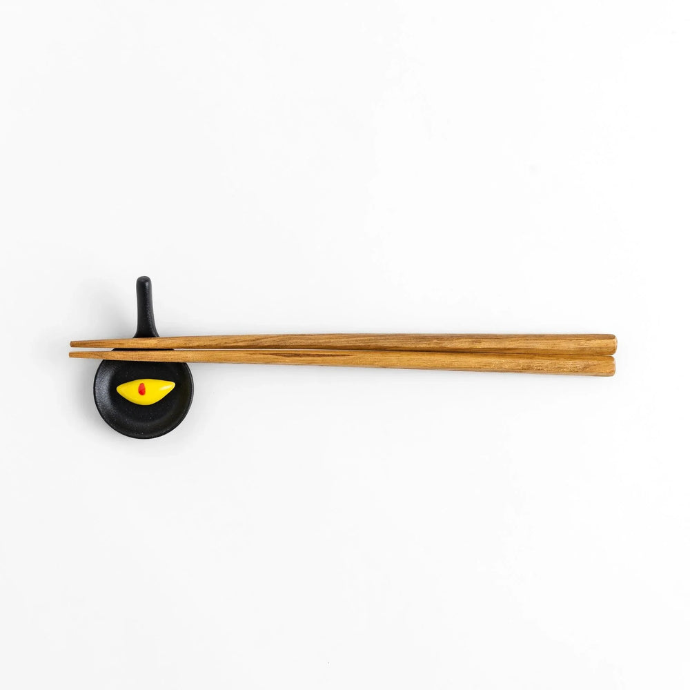 Cute frying pan-shaped chopstick rest with a yellow omelette accent, adding a fun touch to your dining experience.