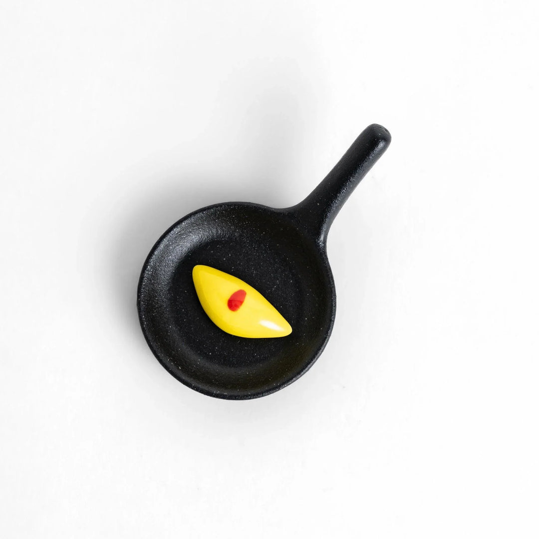 Cute frying pan-shaped chopstick rest with a yellow omelette accent, adding a fun touch to your dining experience.