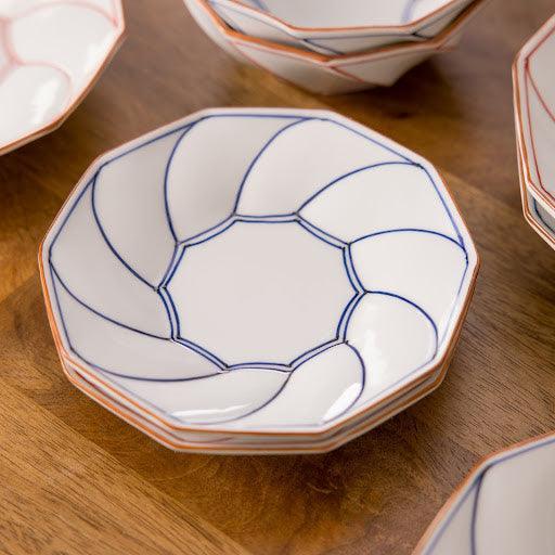 Stacked blue octagonal Japanese dessert plates with geometric blossom rim design and intricate detailing.