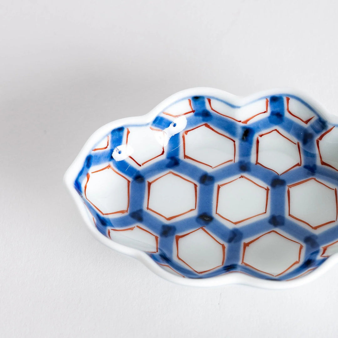 Close-up of the interior of a decorative sauce dish, showcasing the vibrant blue and red hexagonal pattern.